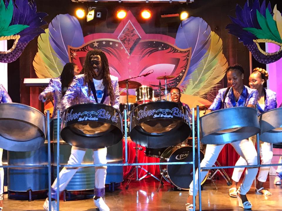 A member of the Silver Birds smiling while playing steel drums